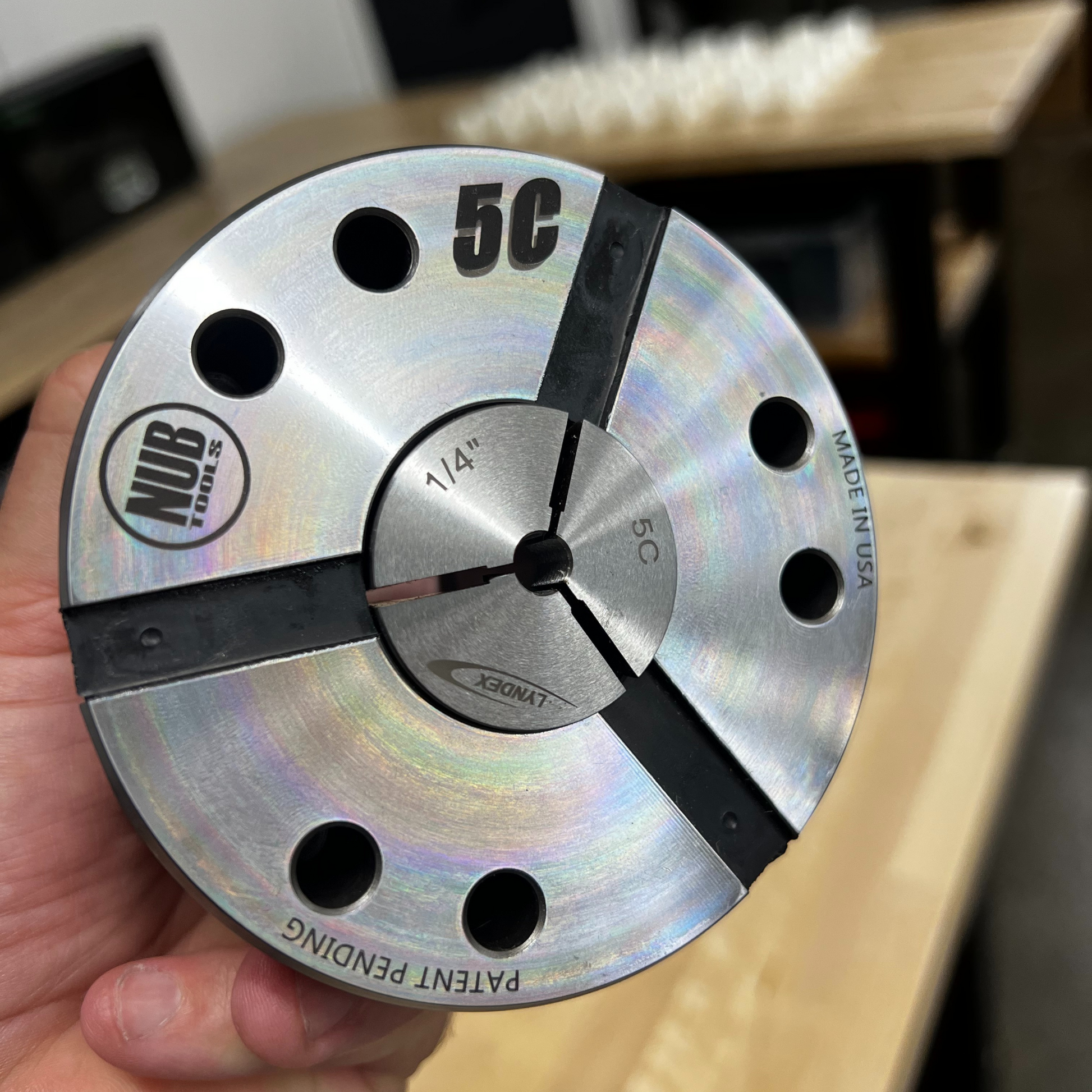 Metal tool with '5C' marking held by a hand, blurred background